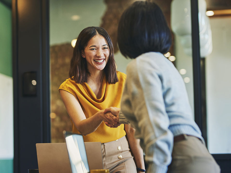 Businesswoman shaking hands with a colleague and smiling cheerfully in meeting room